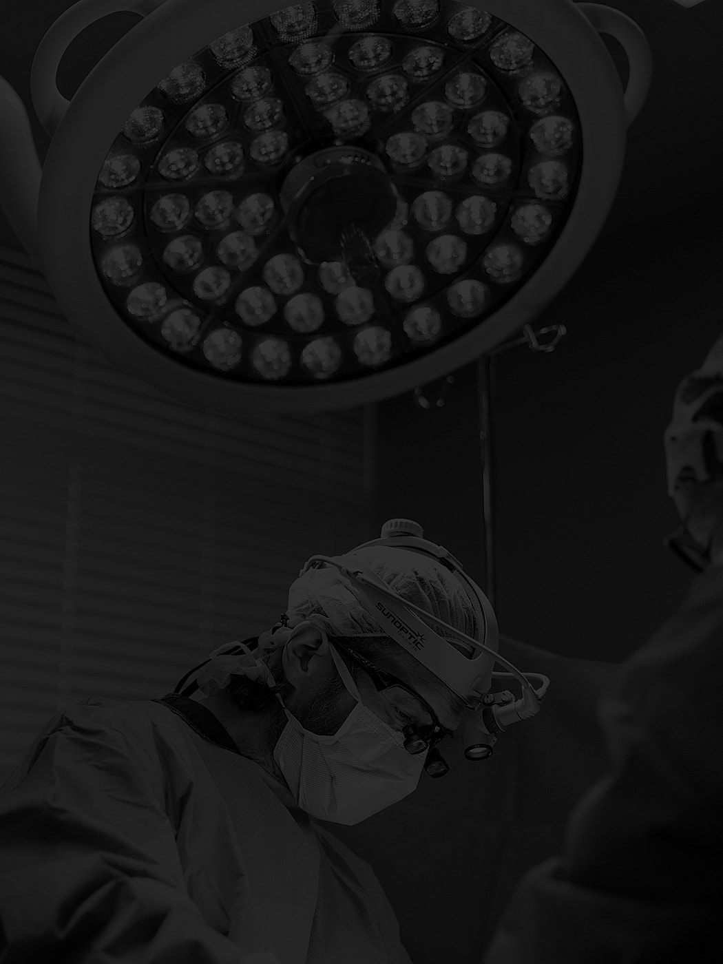 Surgeon focused during an operation under bright lights.