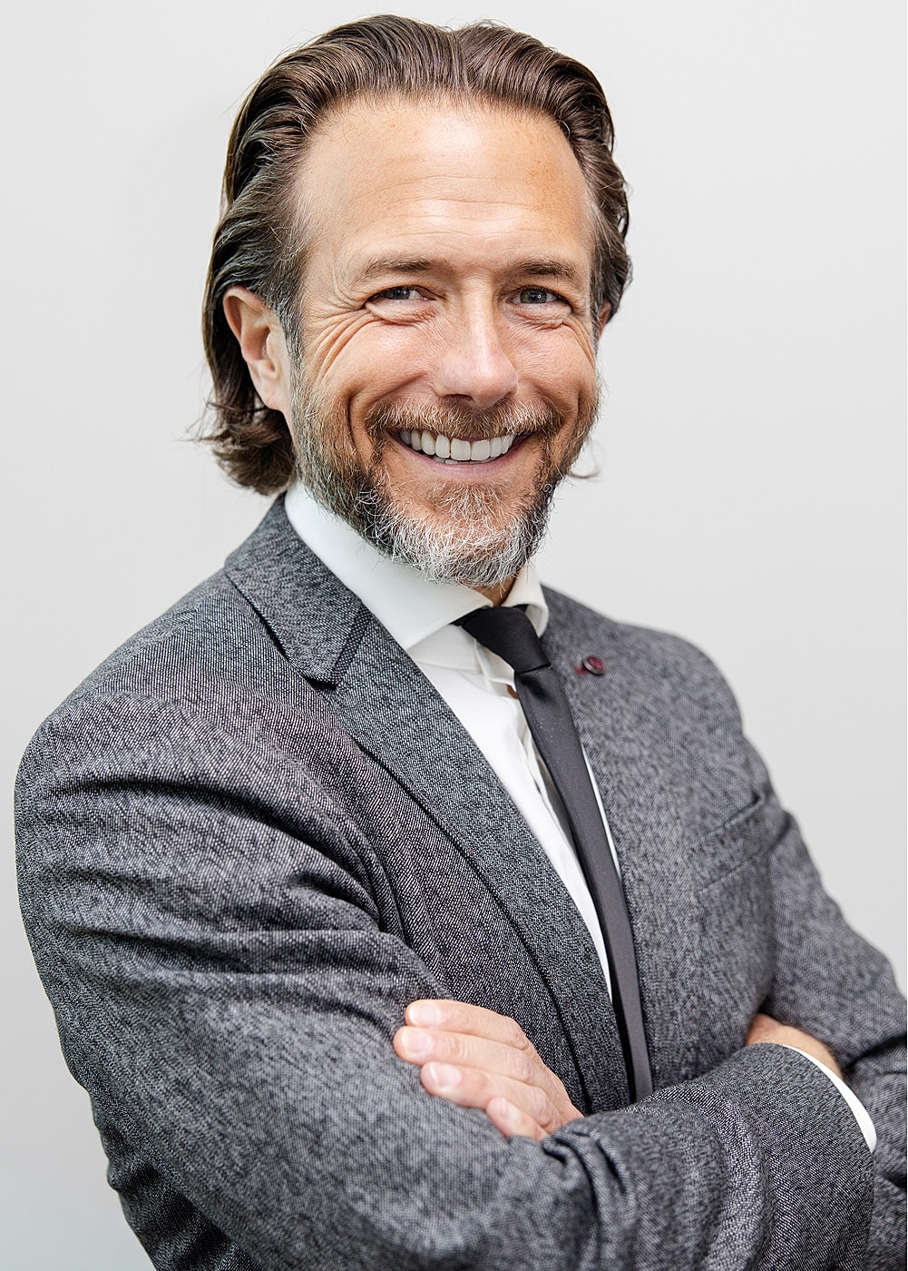 Smiling man in a suit with crossed arms.