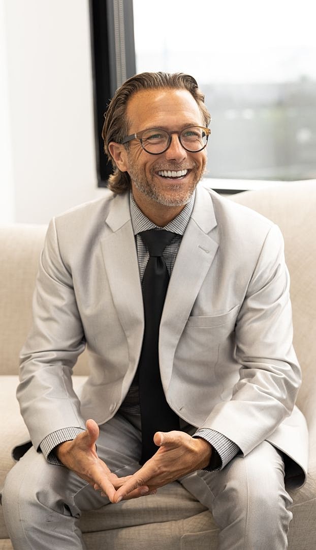 Smiling man in a light grey suit.